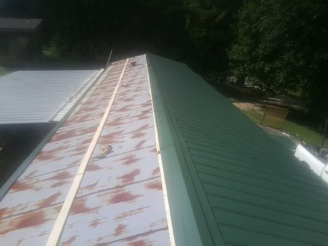 Old rusted panels beside newly installed green metal roofing — Wind Damage Roof Repair by Roofing Brothers in Richville