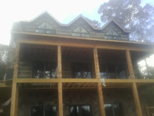 Dormers and porch framing on a large log home under construction — Roof Coating work by our crew in Richville