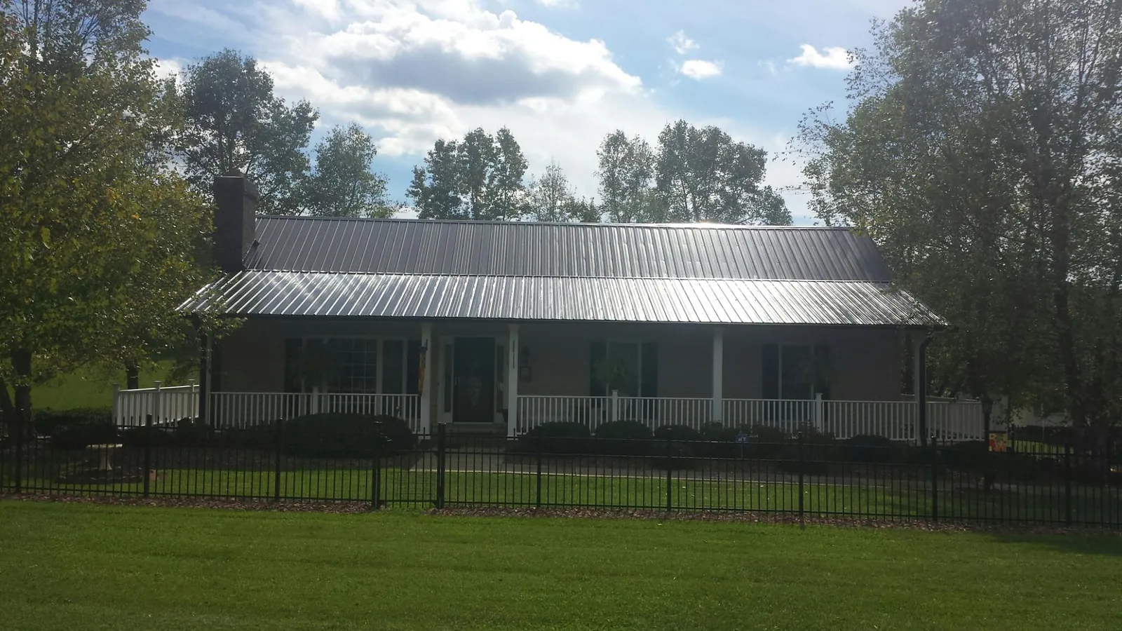 Gray metal roof on a brick ranch with a full width front porch — Gutter Guard Installation work by our crew in Richville