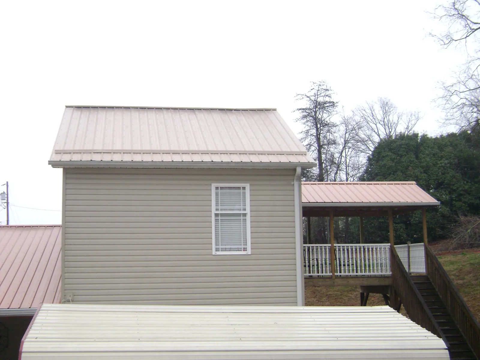 Tan metal roofs on a two story addition and attached porch, from a Roof Replacement job in Richville