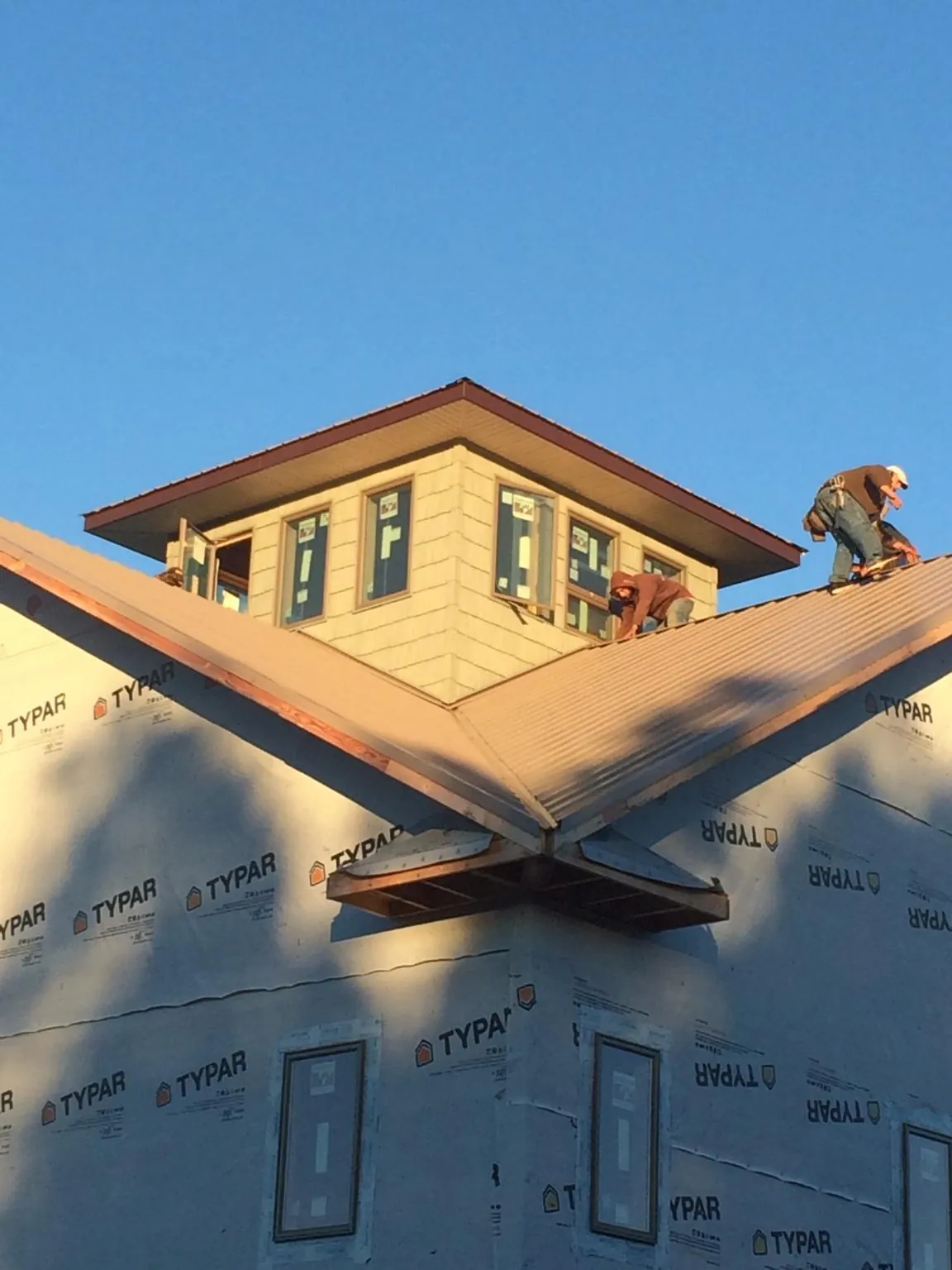 Roofers working around a rooftop cupola on a new metal roof at sunset — Roof Waterproofing in Richville by Roofing Brothers